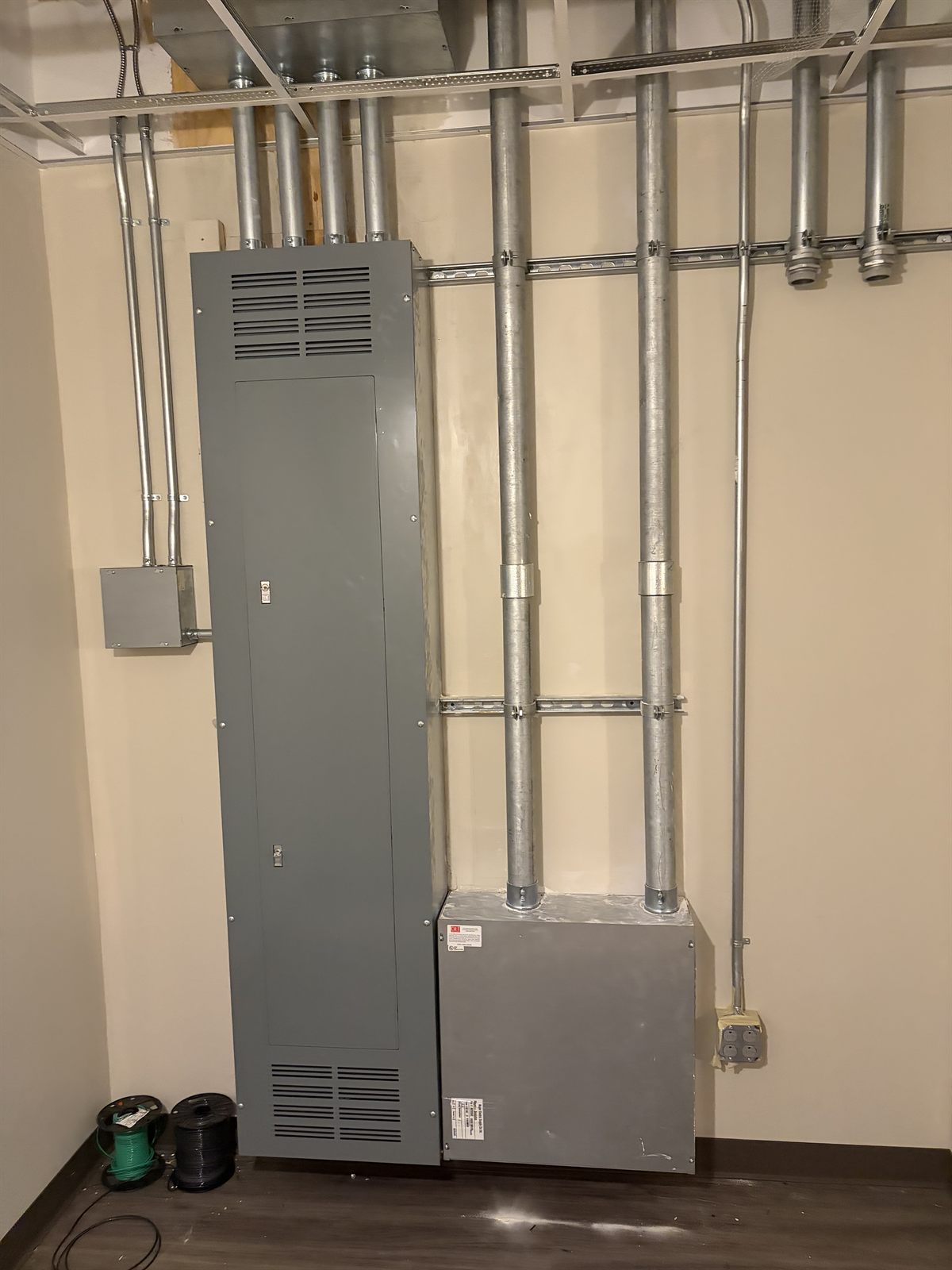 Conduit rack feeding panelboard and transformer in a commercial mechanical room